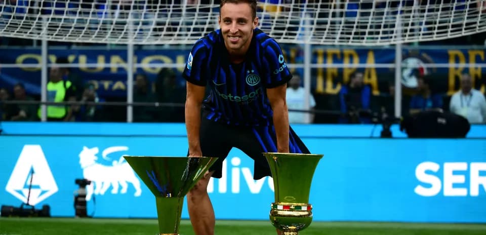Futbolchi ikki kubok bilan maydonda turibdi
