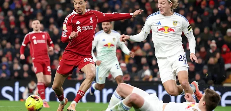 Liverpool player dribbling past Leeds United opponents