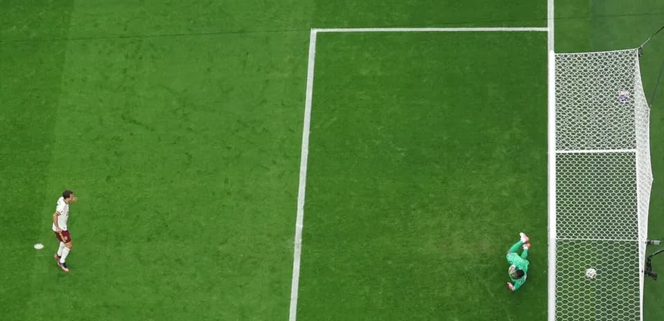 Player approaching goal while goalkeeper prepares to save