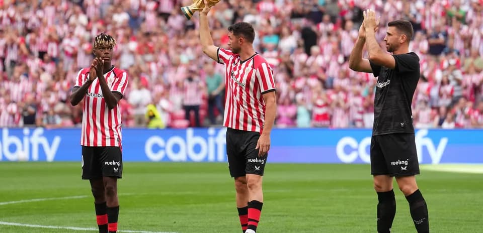 Player holding trophy while teammates applaud fans