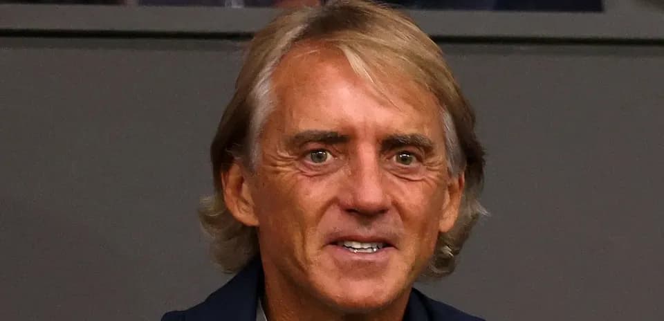 Yuzida turgan futbol murabbiyi kulrang kiyimda
