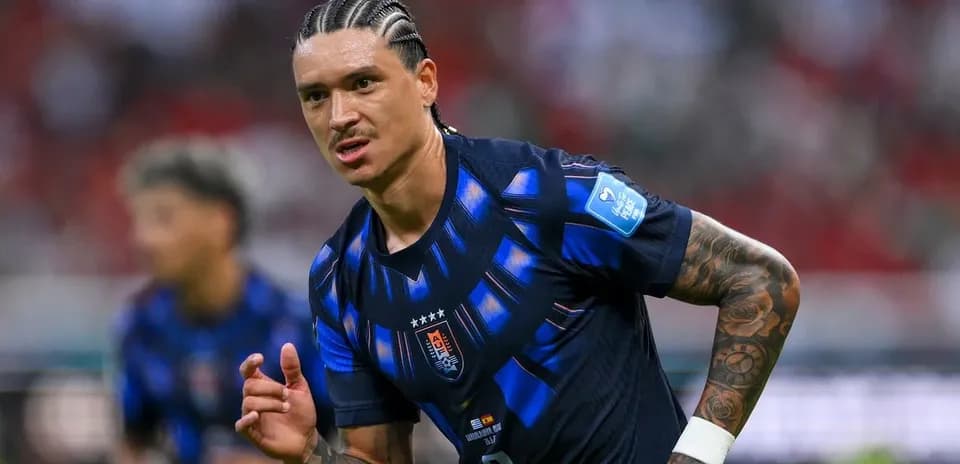 Futbolchi maydonda harakatda, boshqa o'yinchilar ortda