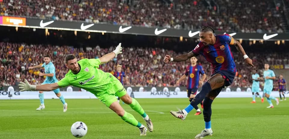 Barcelona player shooting while goalkeeper attempts to save
