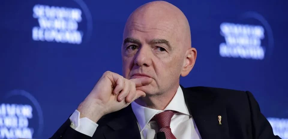 Man speaking at a conference with FIFA logo