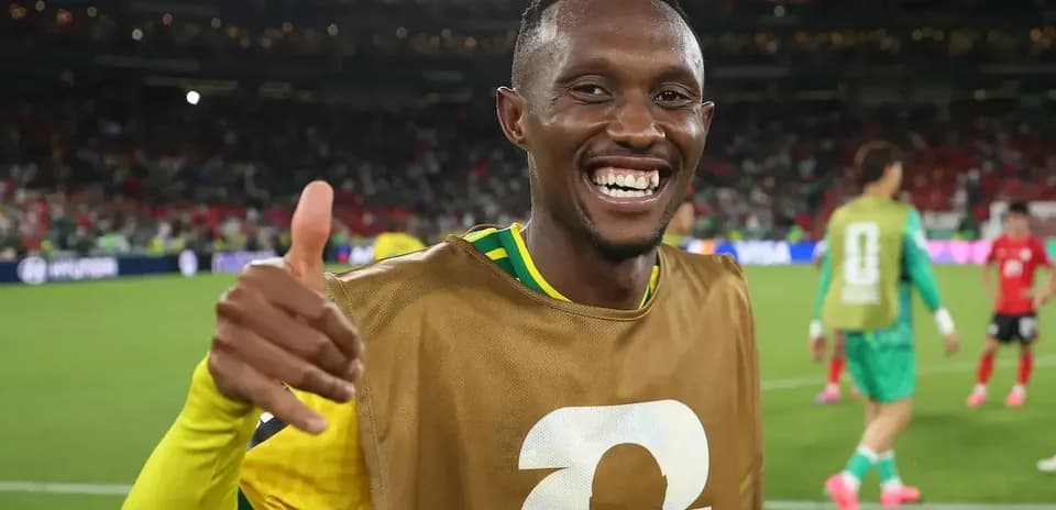 Futbolchi maydonda qo'lni yuqoriga ko'tarib turibdi