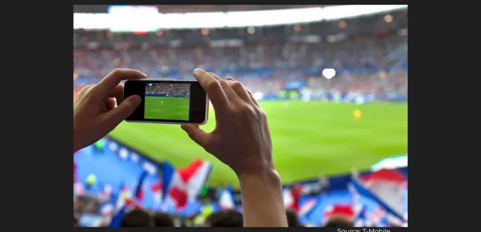 Fan filming football match with smartphone in stadium