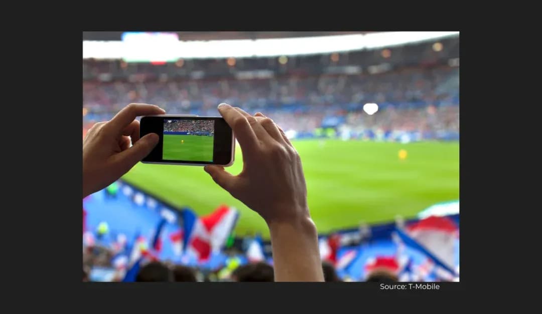 Fan filming football match with smartphone in stadium