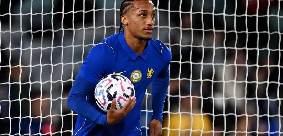 Goalkeeper in blue jersey holding football near goal