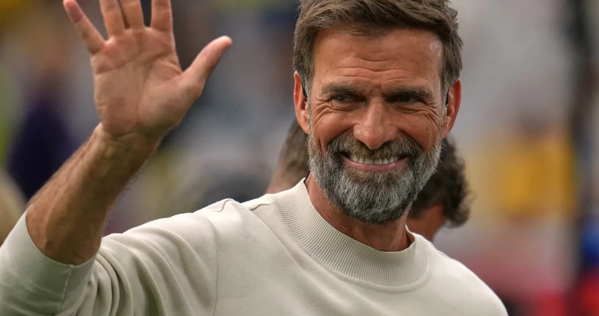 Shaggy-haired man waving during an event