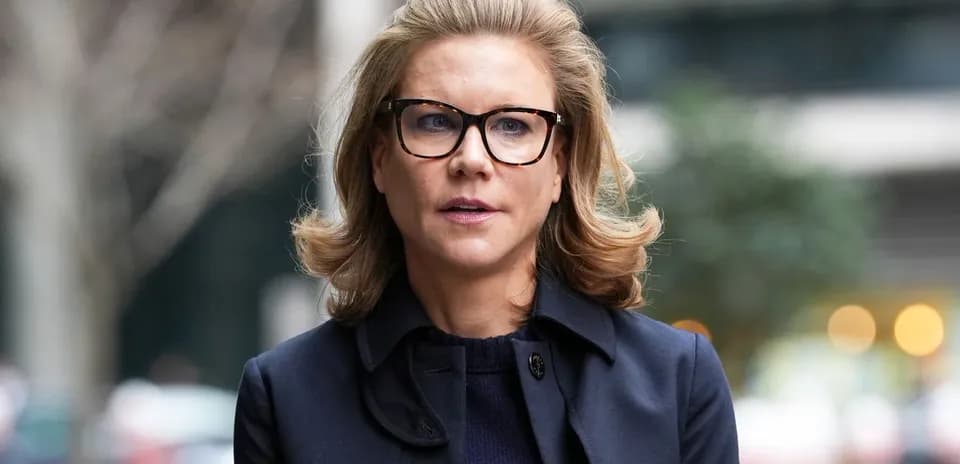 Woman in glasses walking outdoors with trees behind