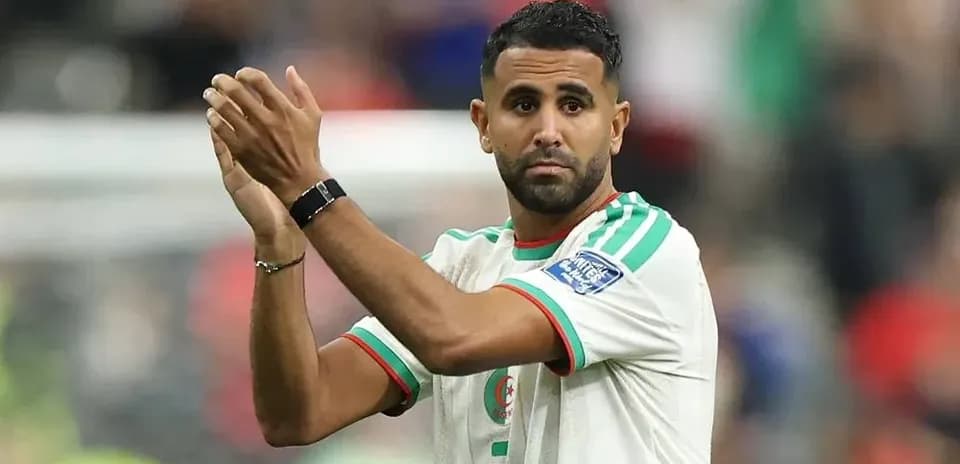 Futbolchi maydonda qo'llarini ko'tarib olqishlamoqda
