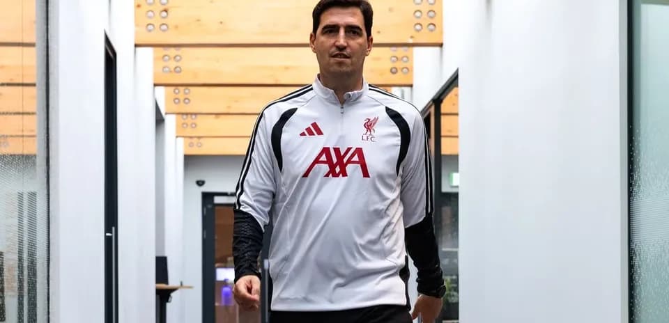 Futbolchi LFC kiyimidagi shaxs koridorda yurmoqda
