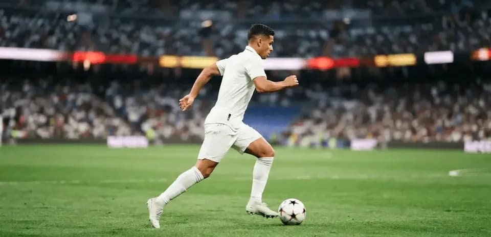 Futbolchi to'p bilan maydon bo'ylab yugurmoqda