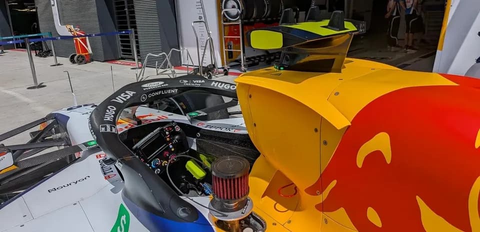 Formula 1 car in pit area with team equipment