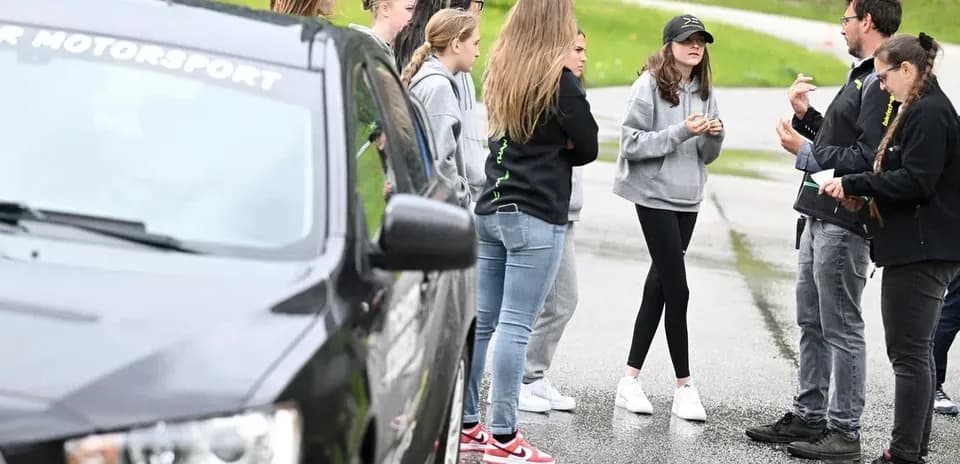 Group discussing near a black car in motorsport event