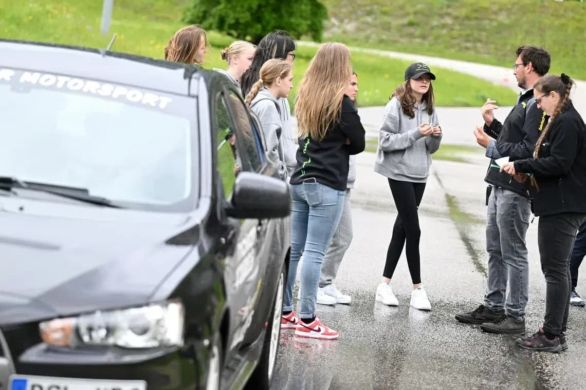 Group discussing near a black car in motorsport event Group discussing near a black car in motorsport event