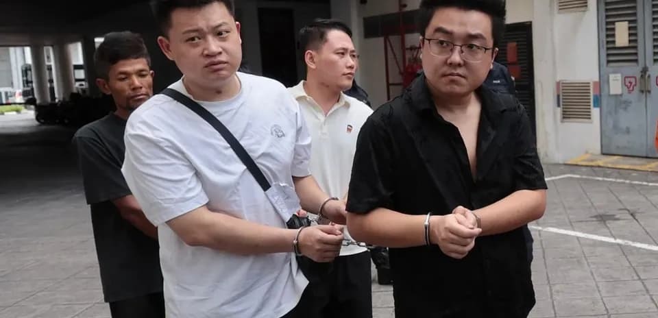 Four individuals in handcuffs walking outside building