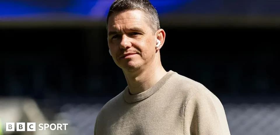 Shirted man standing in stadium with earbuds