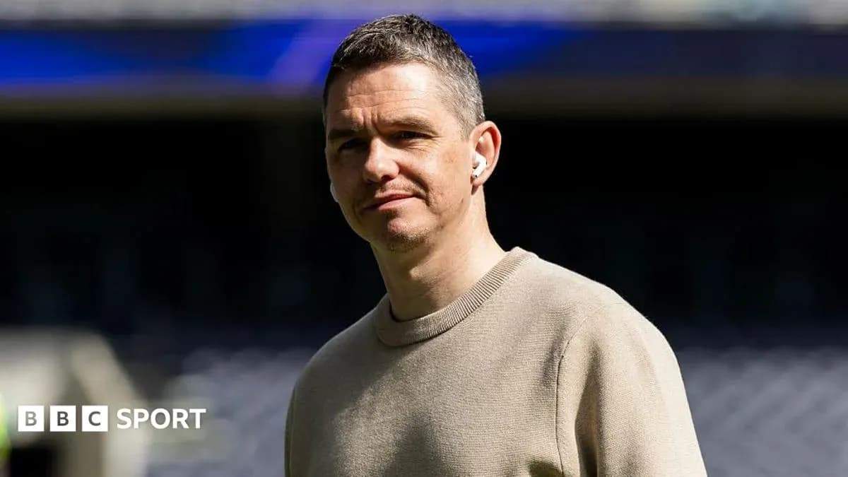 Shirted man standing in stadium with earbuds