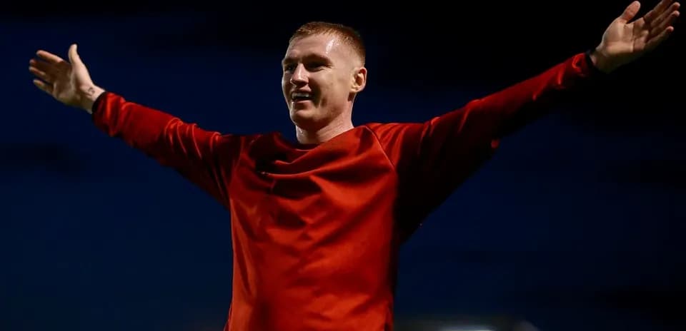 Futbolchi qo'llarini ochib, maydonda turibdi