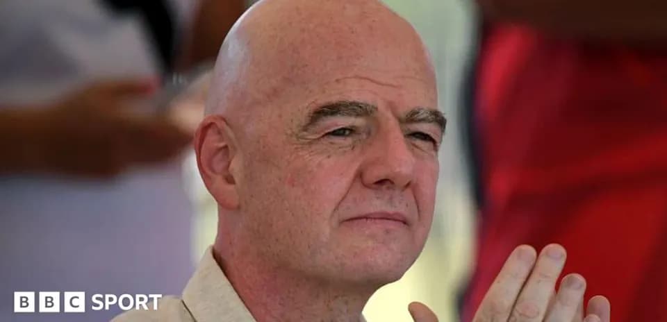 Man with bald head seated, hands clasped together