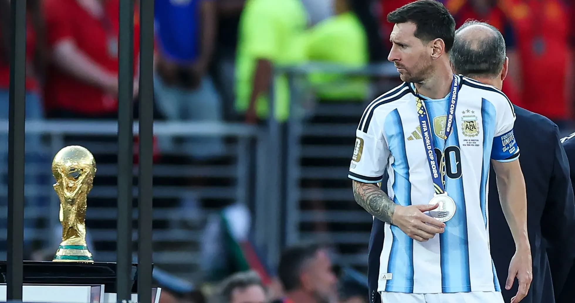 Lionel Messi walking past World Cup trophy
