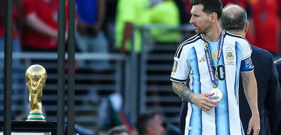 Lionel Messi walking past World Cup trophy