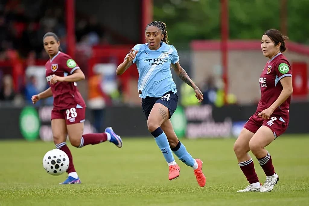 Manchester City player dribbling past West Ham opponents