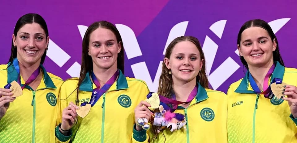 Four swimmers celebrating with gold medals on podium