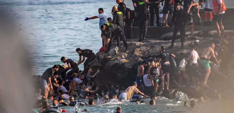 Many people in water and on rocks near shore