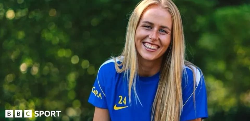 Futbolchi ko'k futbolka kiyib tabassum qilmoqda