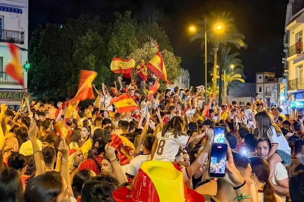 Jubilation of fans celebrating with flags at night