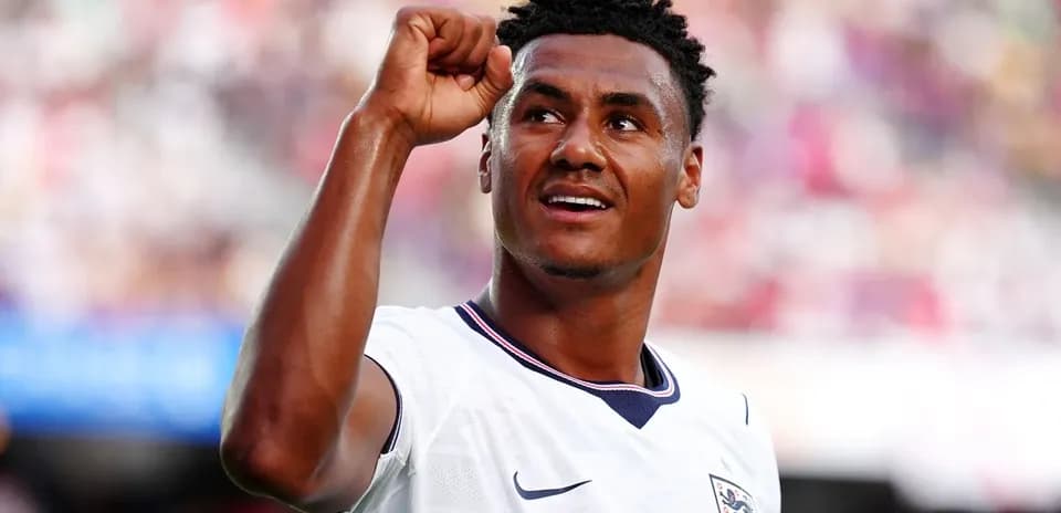 Futbolchi qo'lini ko'tarib, g'alaba belgisini ko'rsatmoqda