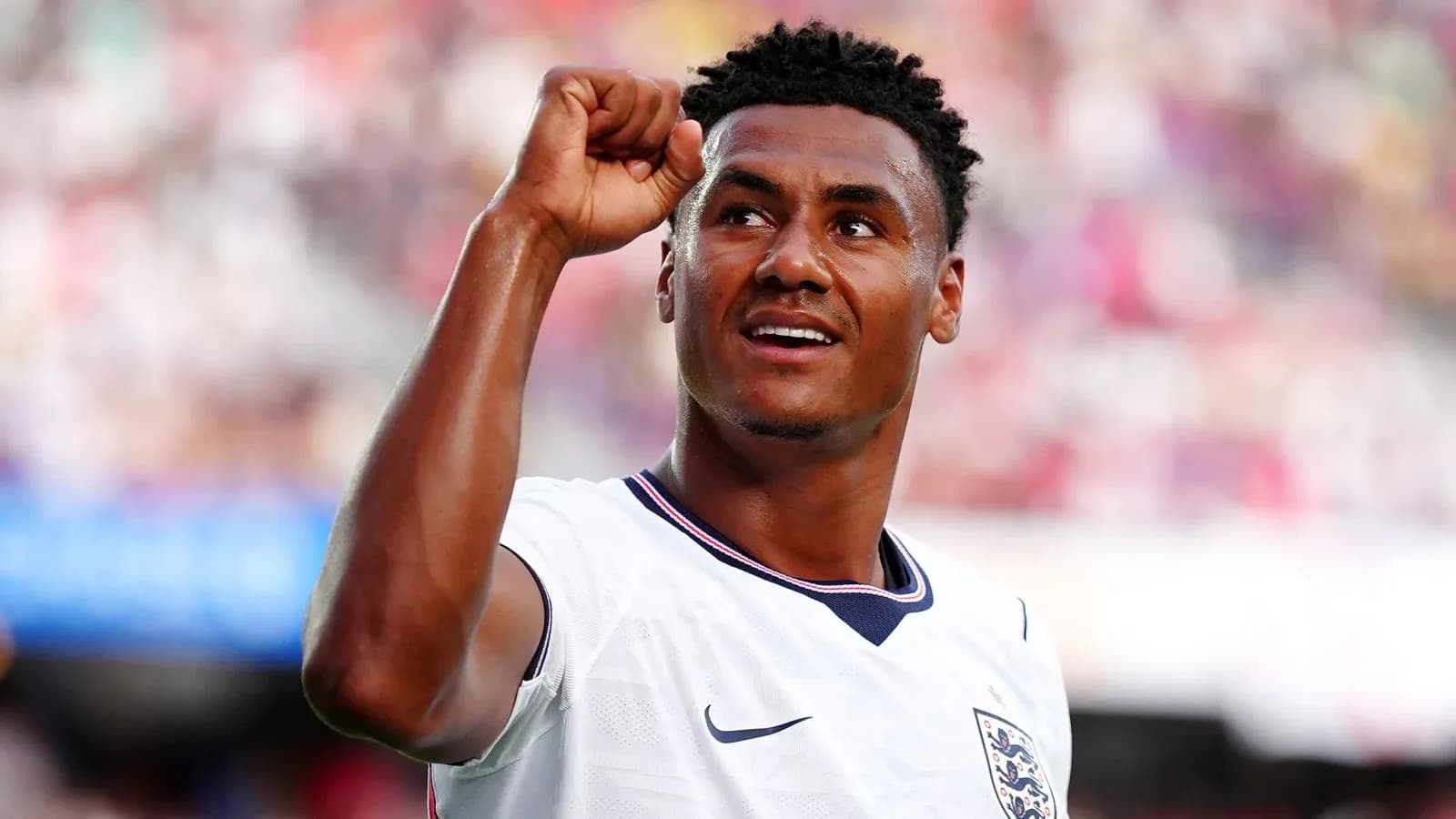 Futbolchi qo'lini ko'tarib, g'alaba belgisini ko'rsatmoqda