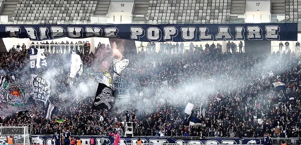 Football fans celebrating with flags and smoke in stadium