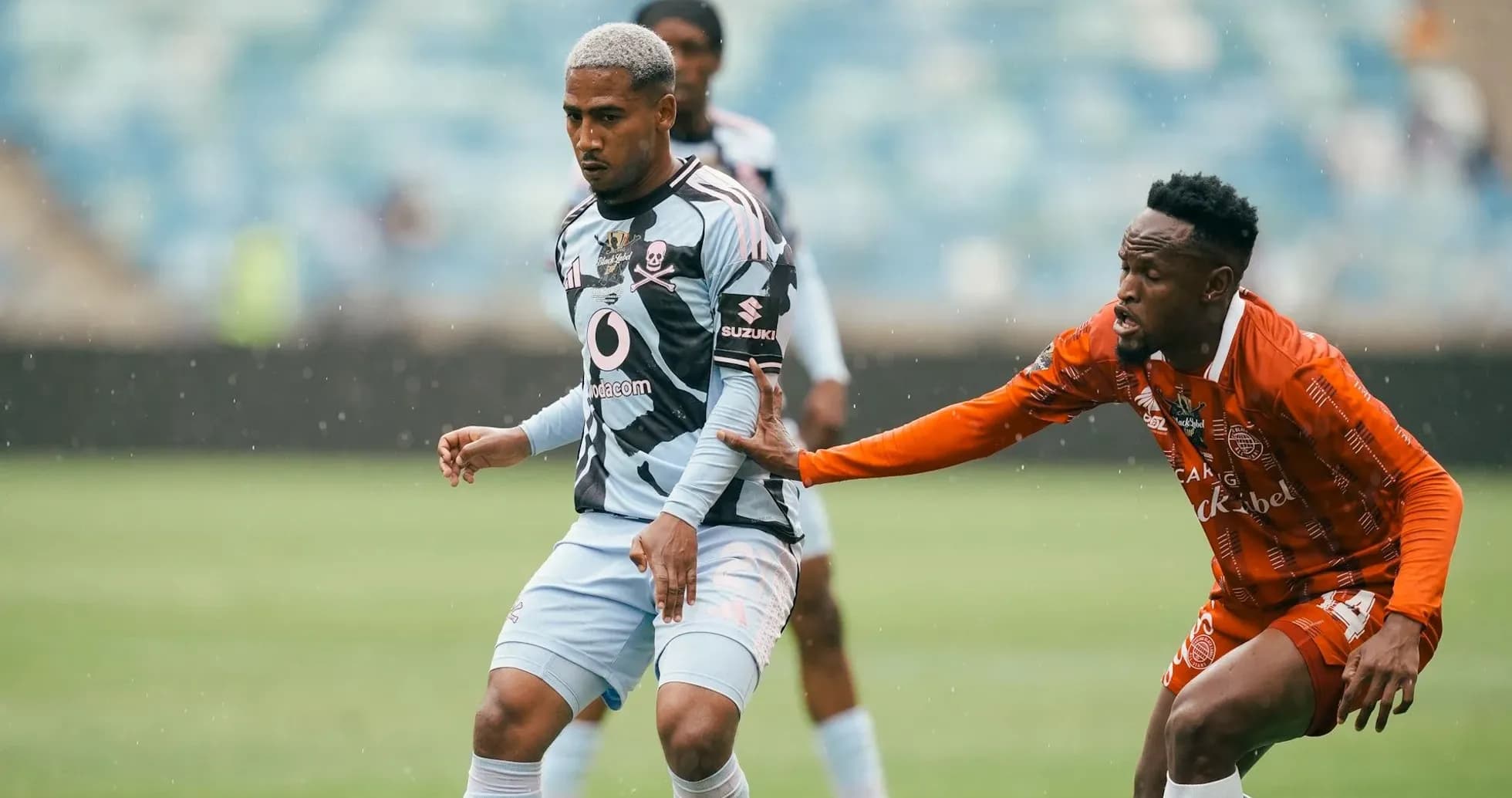 Two players competing for the ball in rain