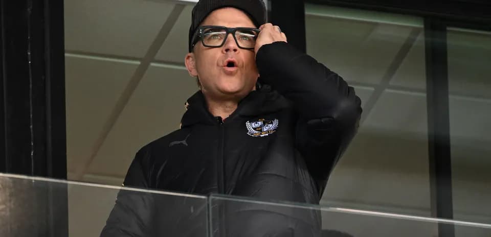 Man in black jacket speaking from a balcony