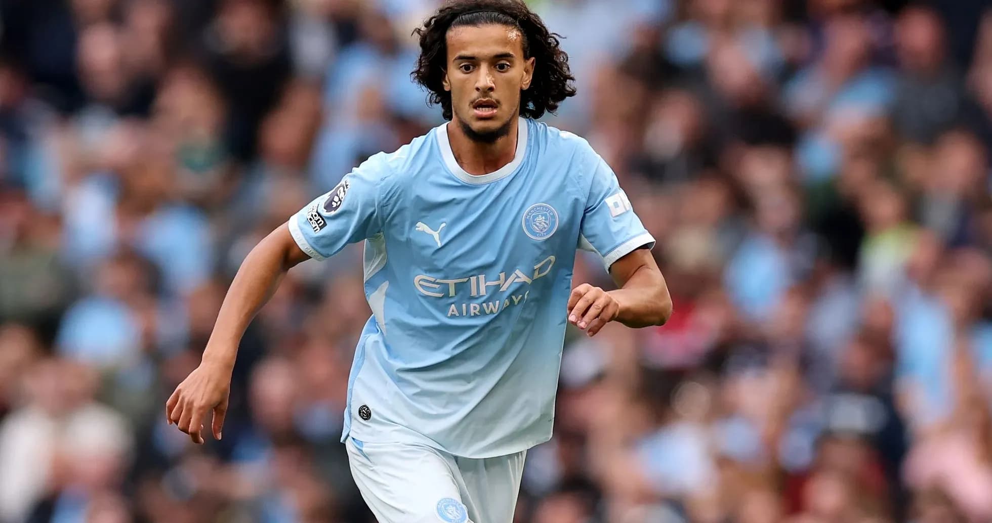 Futbolchi Manchester City formasida to'pni ushlab bormoqda