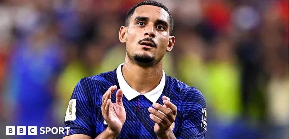 Futbolchi maydonda qo'llarini ko'tarib turibdi