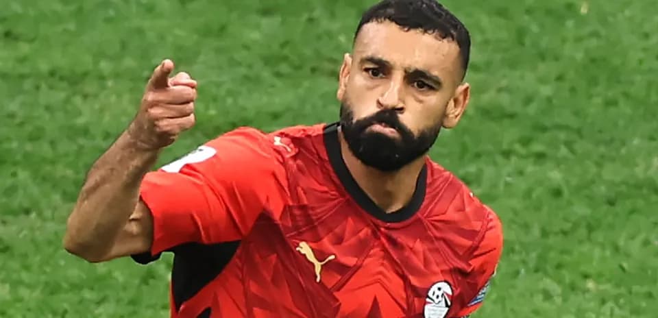 Futbolchi maydonda qo'lini ko'tarib turibdi