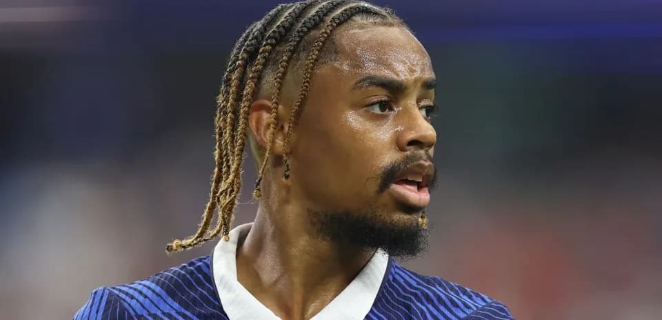 Futbolchi maydonda harakatda, ko'ylagi ko'k chiziqli