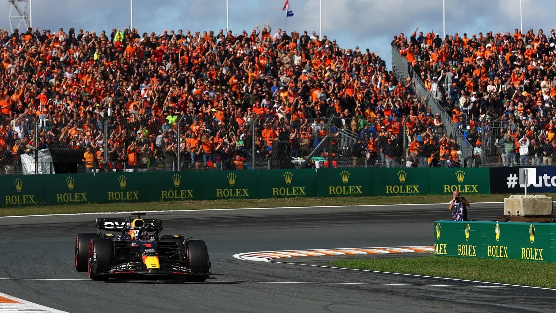 Formula 1 car racing past cheering orange-clad crowd