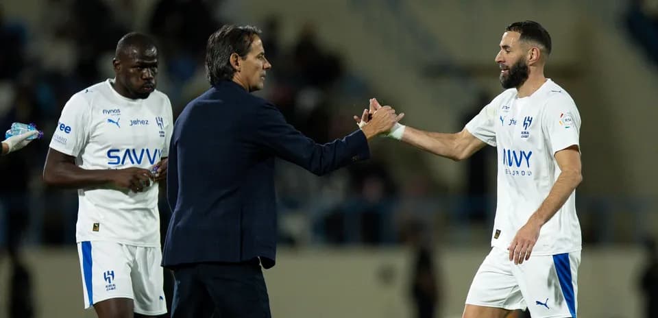 Trener futbolchi bilan qo'l berishmoqda
