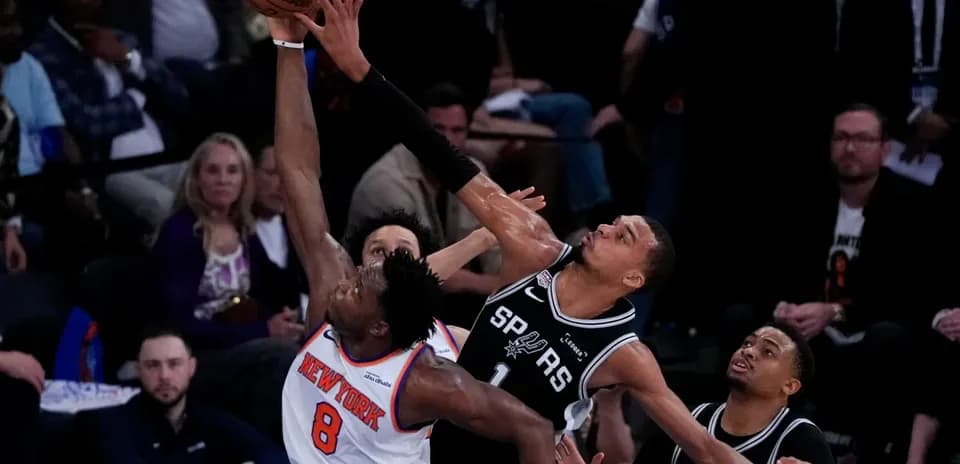 New York player attempting a shot against San Antonio defenders