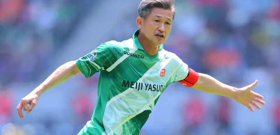 Futbolchi maydonda harakatda, yashil forma kiygan