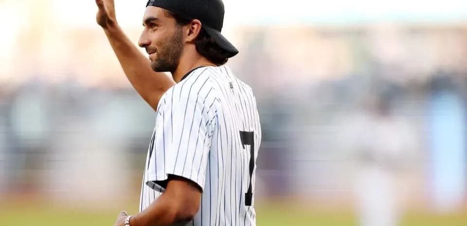 Man waving while wearing baseball jersey at stadium