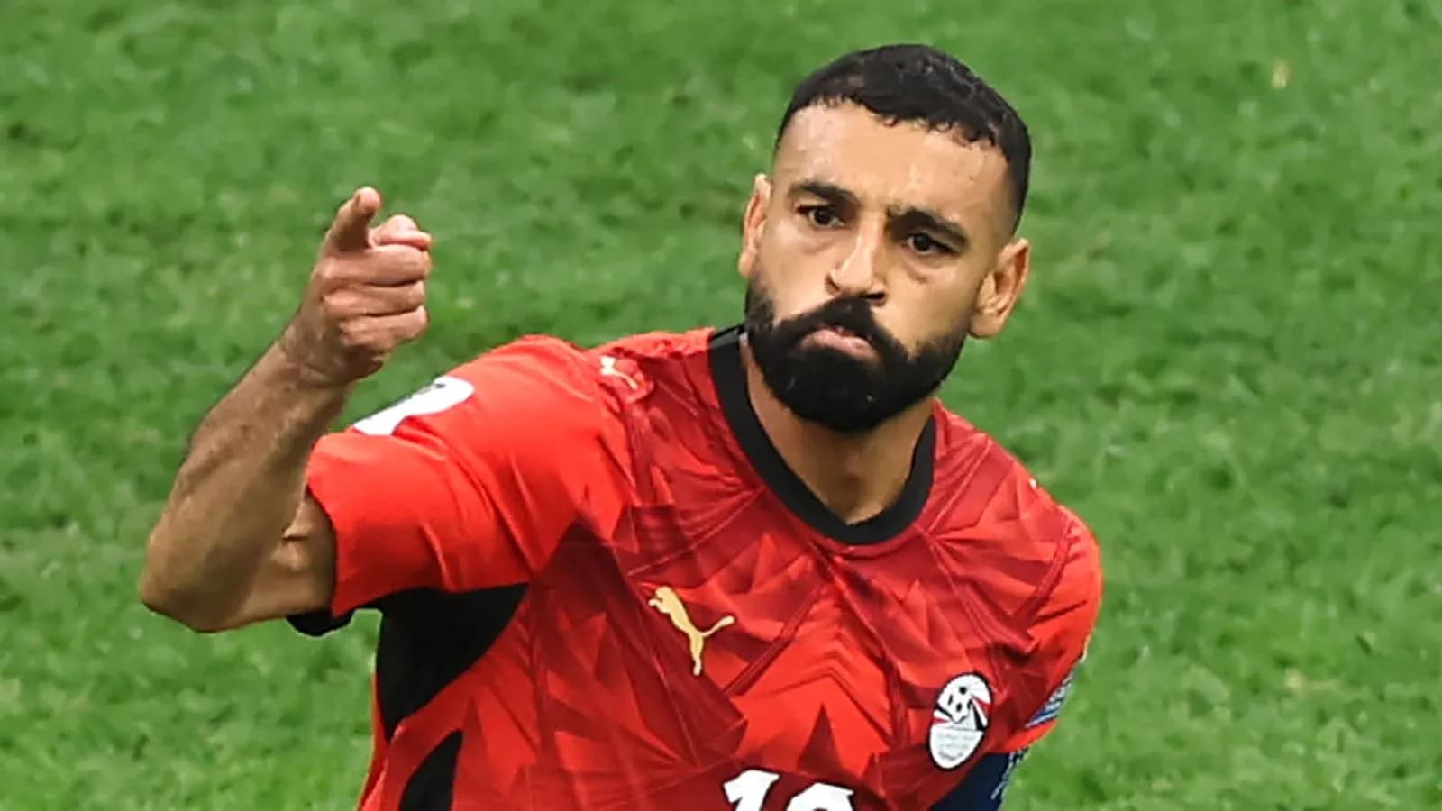 Futbolchi to'pni ko'rsatmoqda, qizil forma kiygan