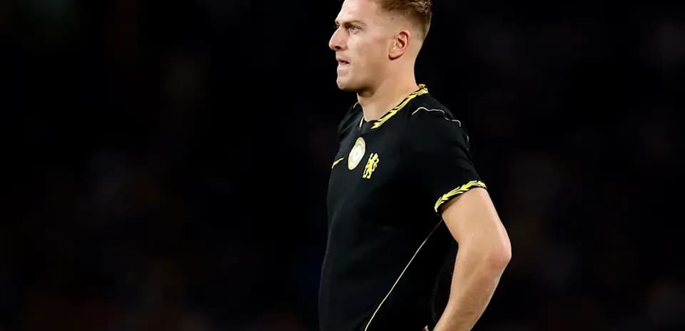 Futbolchi qora forma kiygan holatda turgan