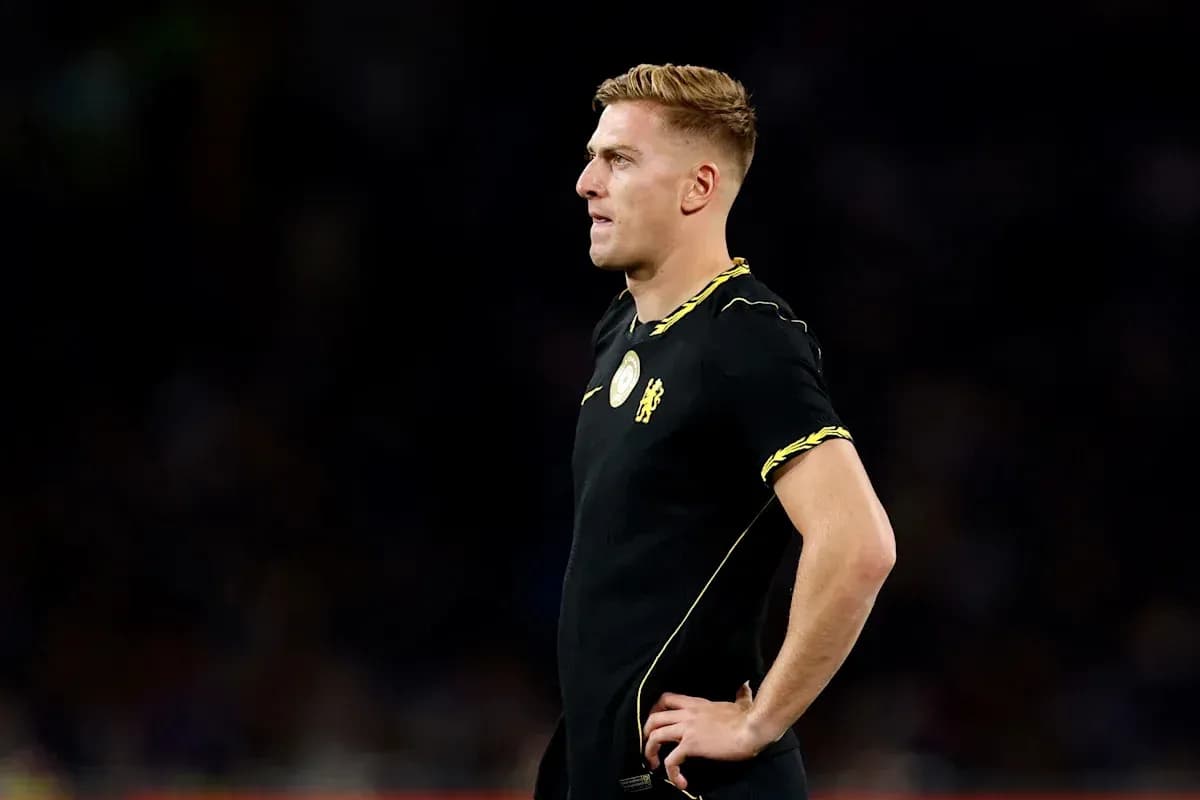 Futbolchi qora forma kiygan holatda turgan
