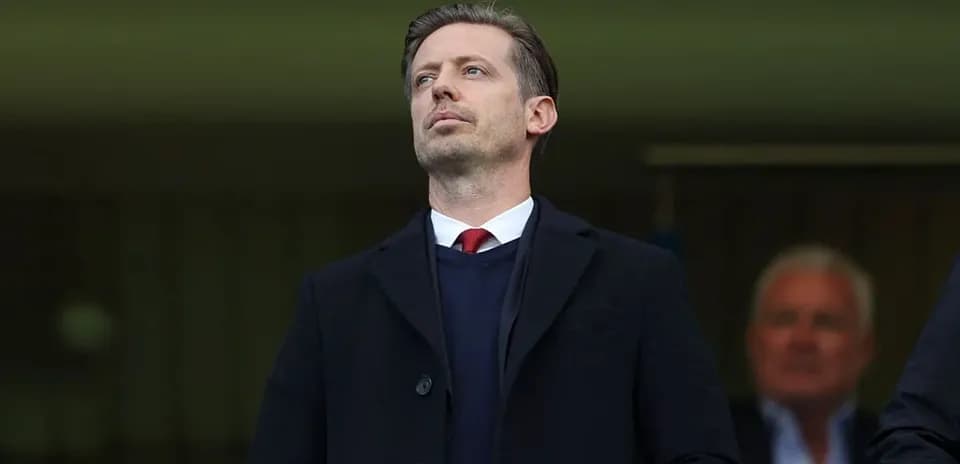Man in black coat observing from a stand